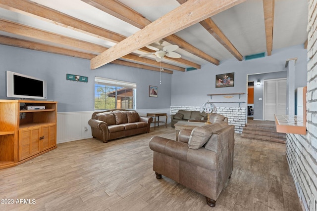 living room featuring light wood-type flooring, ceiling fan, beam ceiling, and a brick fireplace