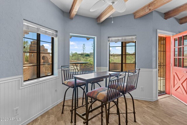 dining space with ceiling fan, beamed ceiling, and light hardwood / wood-style flooring