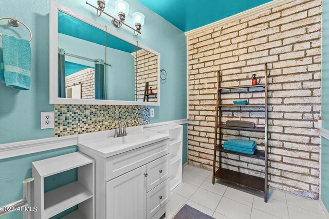 bathroom featuring vanity, tasteful backsplash, brick wall, and tile patterned flooring