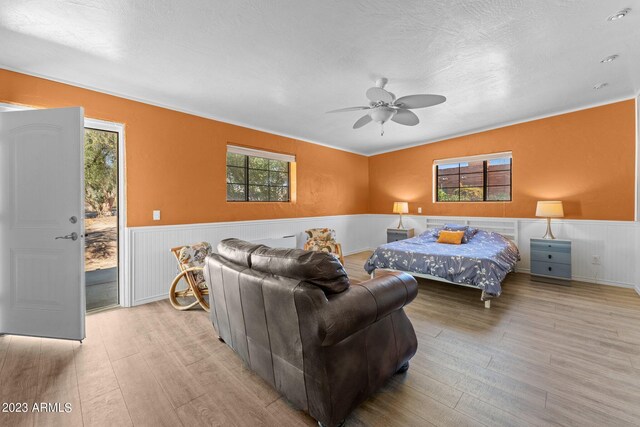 bedroom with ceiling fan, a textured ceiling, access to outside, and light hardwood / wood-style flooring