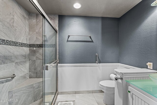 bathroom featuring a shower with shower door, toilet, and vanity