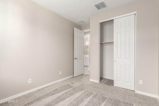 unfurnished bedroom with light colored carpet and a closet