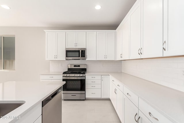 kitchen featuring stainless steel appliances, light tile patterned floors, tasteful backsplash, and white cabinetry