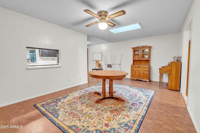 living area with ceiling fan, a skylight, and a textured ceiling