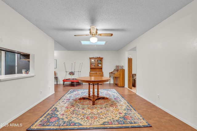 interior space featuring ceiling fan, a skylight, and a textured ceiling