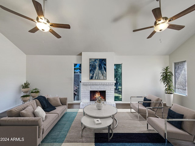 living room with hardwood / wood-style floors, a healthy amount of sunlight, vaulted ceiling, and a brick fireplace