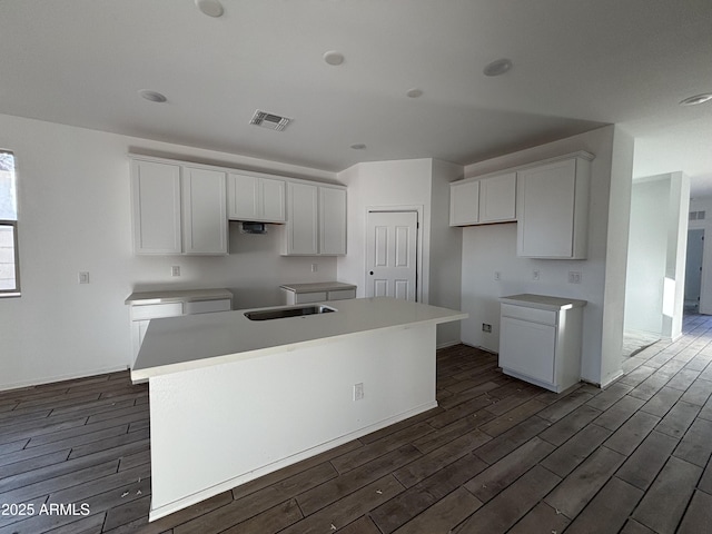 kitchen with white cabinetry, a kitchen island, sink, and dark hardwood / wood-style flooring