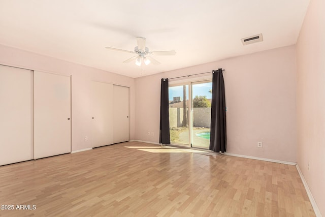 unfurnished bedroom with multiple closets, access to outside, ceiling fan, and light hardwood / wood-style flooring