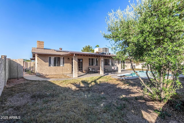 rear view of property with a fenced in pool and a patio area