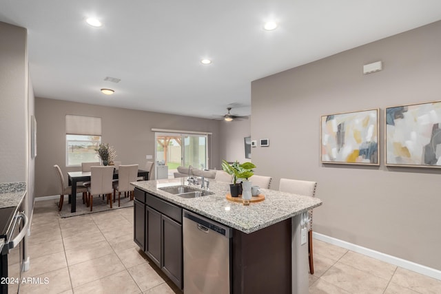 kitchen featuring sink, ceiling fan, light stone countertops, an island with sink, and appliances with stainless steel finishes