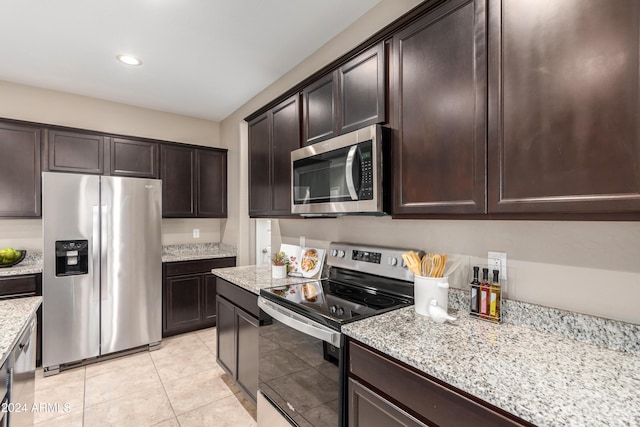 kitchen featuring dark brown cabinets, light tile patterned flooring, light stone countertops, and stainless steel appliances