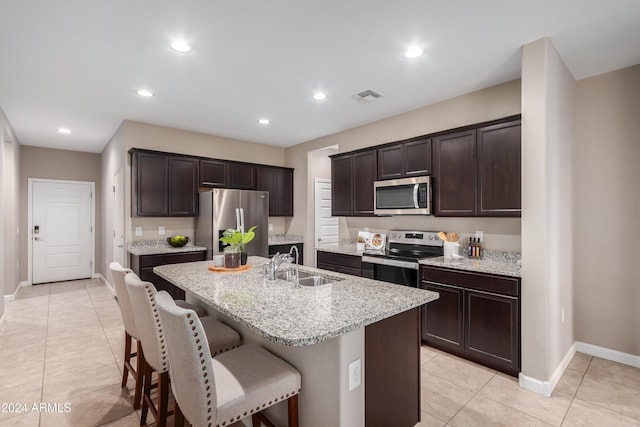 kitchen with a center island with sink, a kitchen breakfast bar, sink, appliances with stainless steel finishes, and dark brown cabinets