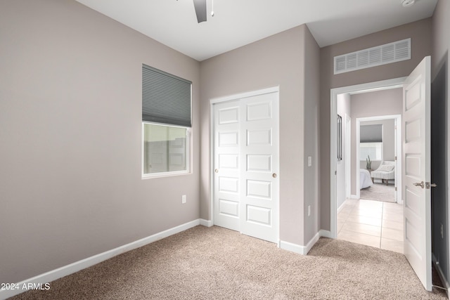 unfurnished bedroom with ceiling fan, a closet, and light colored carpet