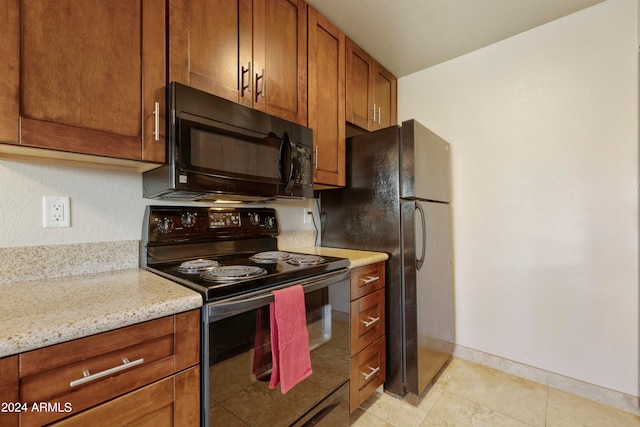 kitchen with black appliances, light tile patterned flooring, and light stone counters