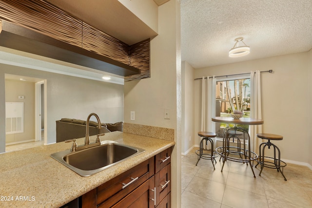 kitchen featuring sink, a textured ceiling, and light tile patterned floors