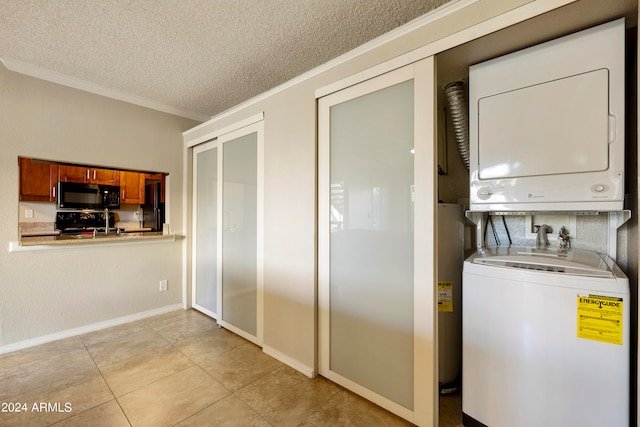 laundry area featuring light tile patterned floors, a textured ceiling, water heater, stacked washer and dryer, and crown molding