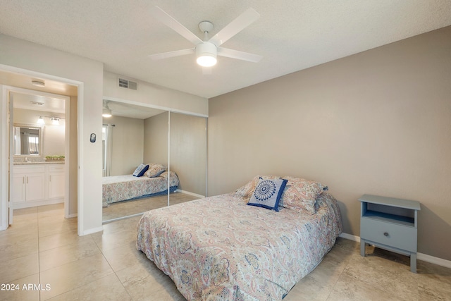 bedroom featuring a closet, a textured ceiling, light tile patterned floors, and ceiling fan