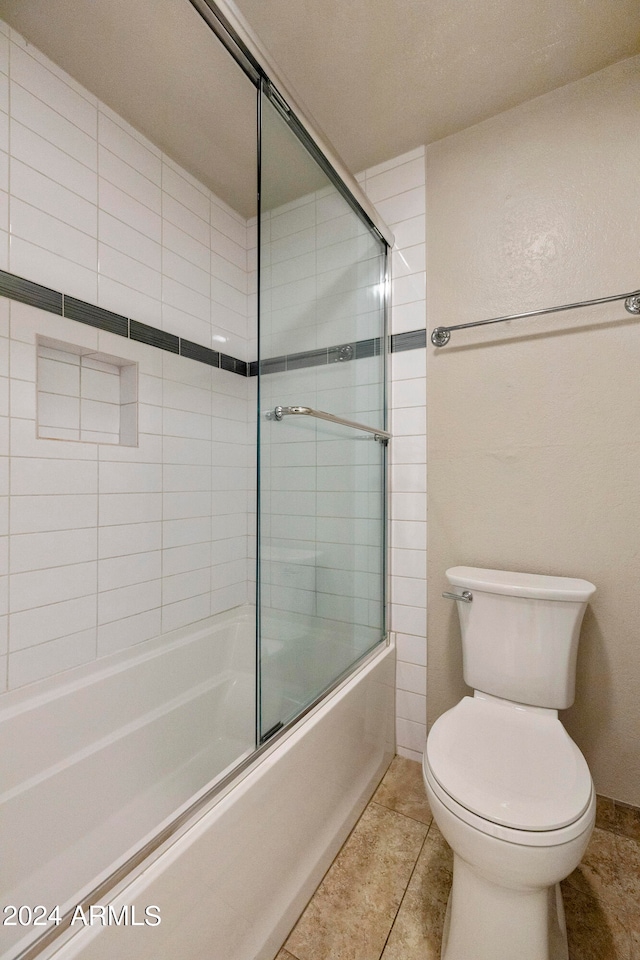 bathroom with toilet, enclosed tub / shower combo, and tile patterned flooring