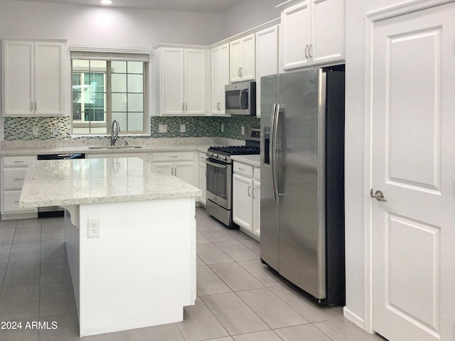 kitchen featuring light stone counters, stainless steel appliances, sink, white cabinets, and a kitchen island