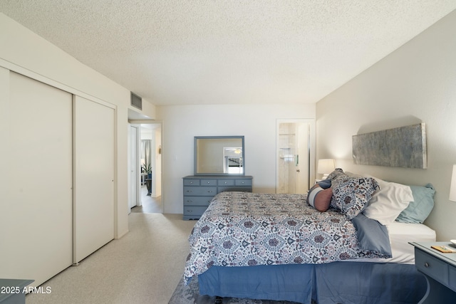 carpeted bedroom featuring a closet, visible vents, and a textured ceiling