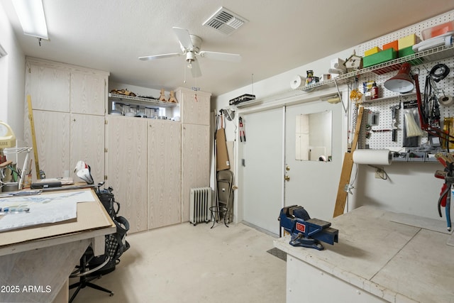 basement featuring a ceiling fan, radiator, and visible vents