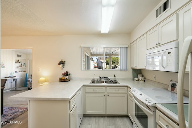 kitchen with light countertops, white appliances, visible vents, and a sink