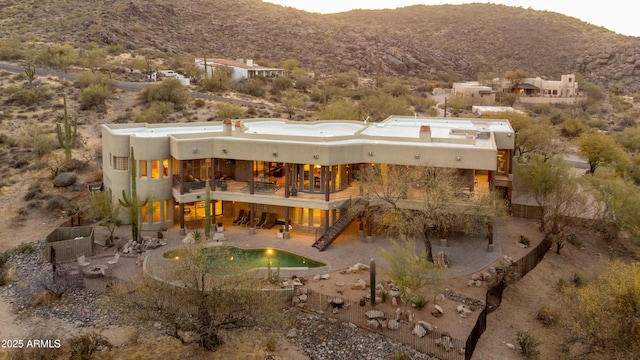 rear view of property featuring a balcony, stairway, stucco siding, a patio area, and a mountain view