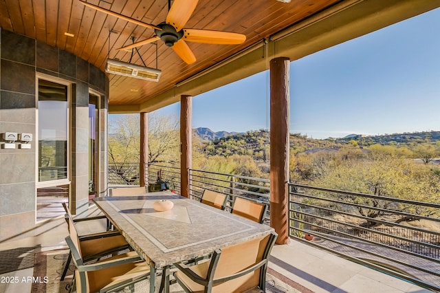 view of patio with outdoor dining space, ceiling fan, a forest view, and a balcony