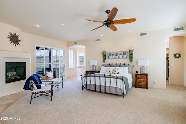 carpeted bedroom featuring recessed lighting, arched walkways, and visible vents