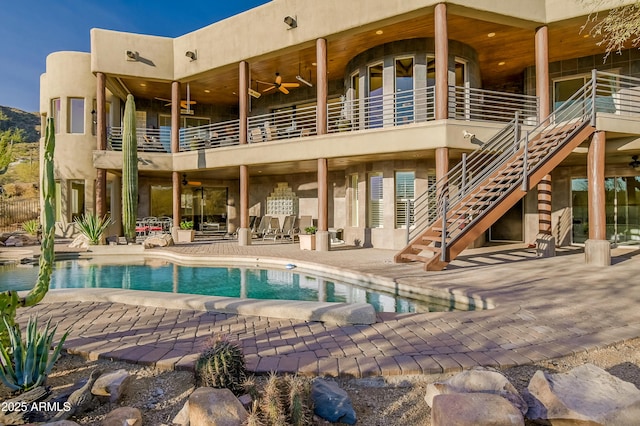 outdoor pool with ceiling fan, stairs, and a patio area