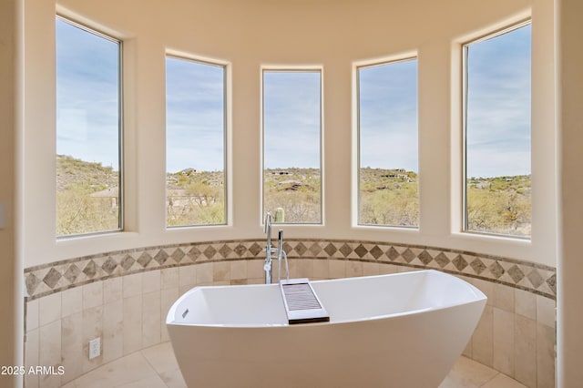 full bath with a soaking tub, wainscoting, tile walls, and a sink