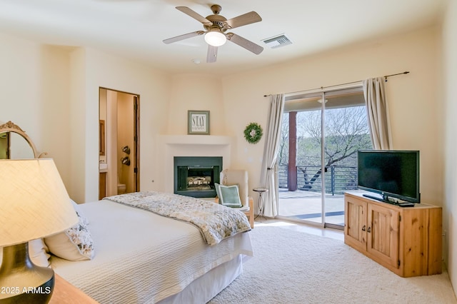 carpeted bedroom featuring ceiling fan, access to exterior, visible vents, and a large fireplace