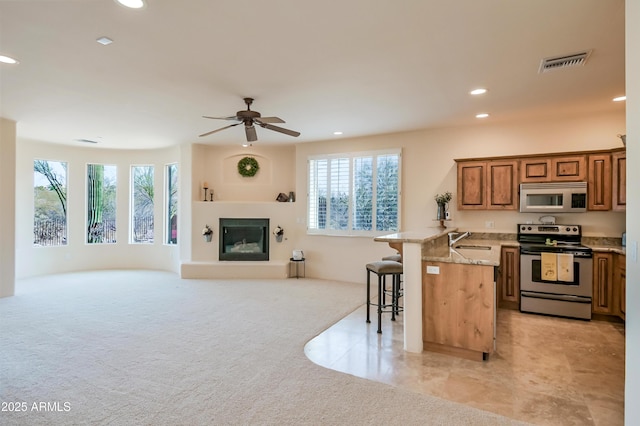 kitchen with visible vents, open floor plan, a kitchen bar, stainless steel electric range, and a peninsula