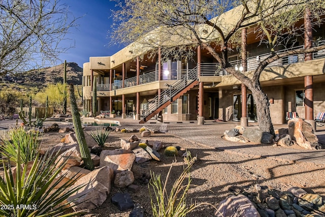 back of house with stairway, a patio, and a mountain view