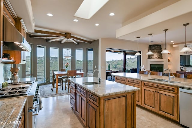 kitchen featuring brown cabinetry, a fireplace, stainless steel appliances, and a sink