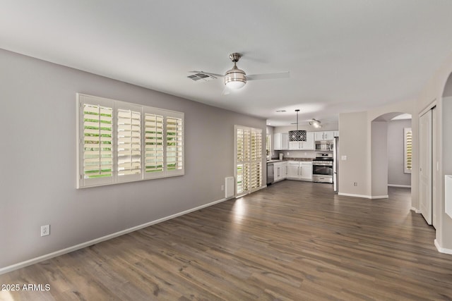 2438 W Via Dona Rd, Phoenix, AZ 85085 - unfurnished living room featuring arched walkways, ceiling fan, healthy amount of natural light, and baseboards