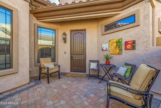 entrance to property with a tile roof, a patio area, and stucco siding