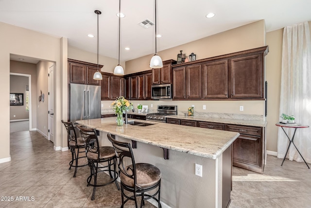 kitchen with visible vents, dark brown cabinetry, a kitchen breakfast bar, stainless steel appliances, and a sink