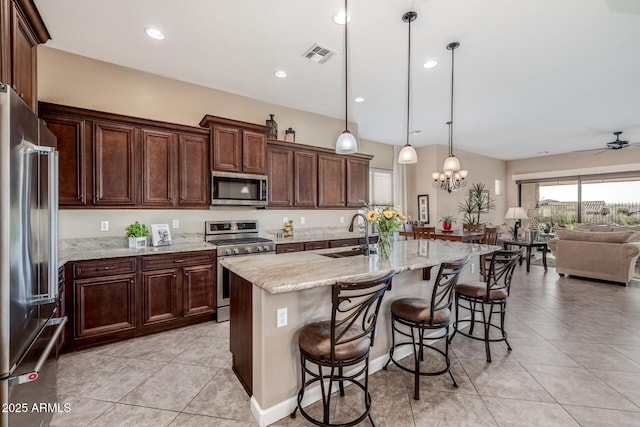 kitchen with visible vents, open floor plan, a breakfast bar, stainless steel appliances, and a sink