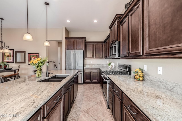 kitchen with a sink, stainless steel appliances, light stone counters, and decorative light fixtures