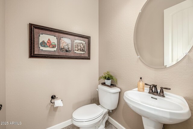 bathroom featuring toilet, baseboards, and a sink