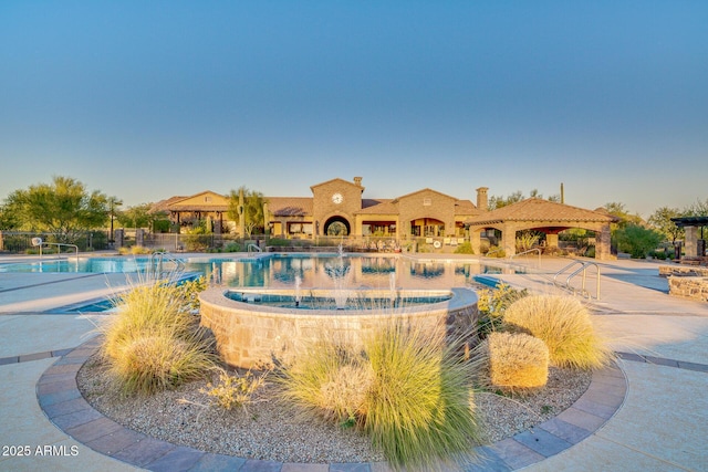 community pool with a gazebo and fence