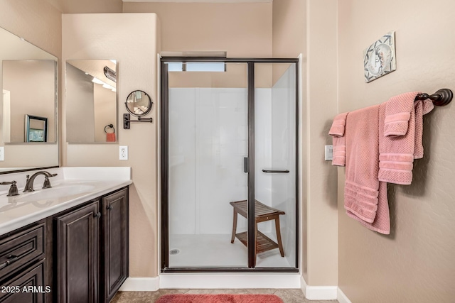 bathroom featuring baseboards, a stall shower, and vanity