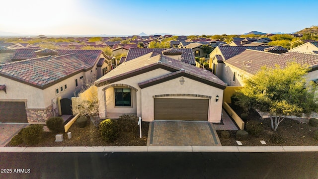 mediterranean / spanish home with a residential view, stucco siding, an attached garage, and decorative driveway