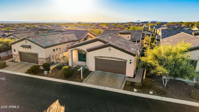 mediterranean / spanish house featuring stucco siding, an attached garage, a tile roof, and decorative driveway