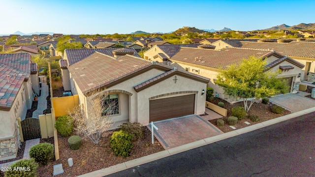 view of front of home featuring a tile roof, stucco siding, decorative driveway, a garage, and a mountain view