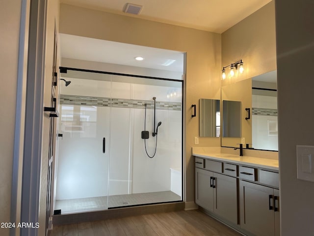 bathroom with hardwood / wood-style floors, vanity, and a shower with shower door