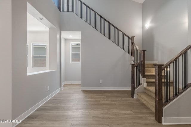 stairs featuring hardwood / wood-style floors and a towering ceiling