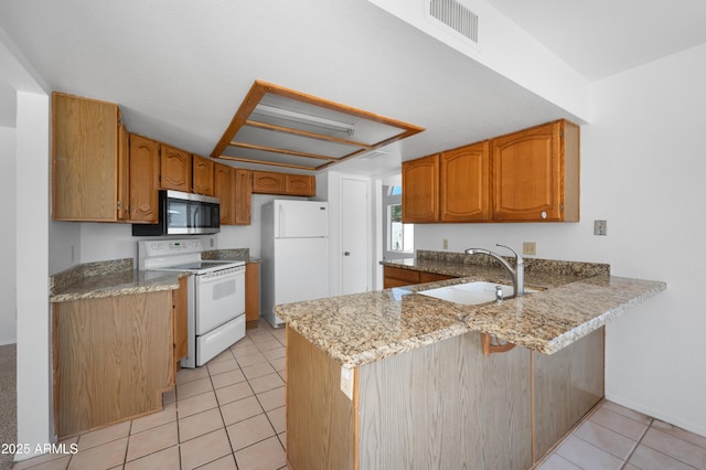 kitchen featuring white appliances, light tile patterned flooring, visible vents, a sink, and a peninsula