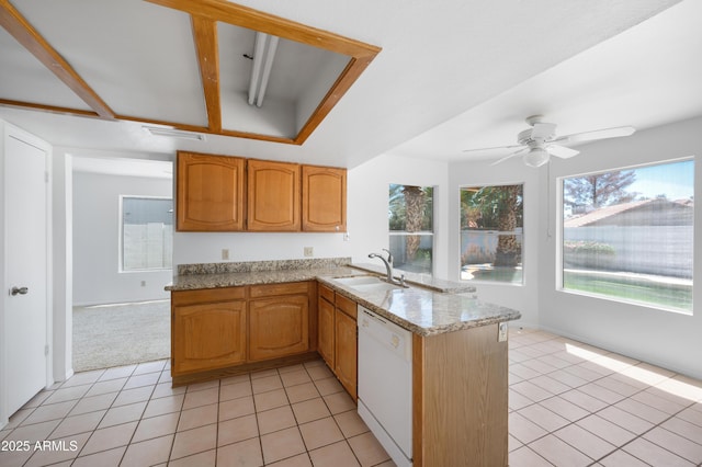 kitchen with a sink, a peninsula, light tile patterned flooring, white dishwasher, and light stone countertops